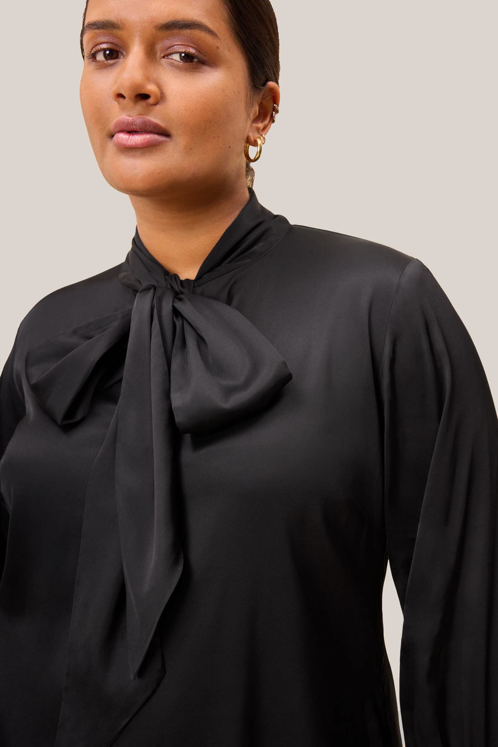 Close-up of bow tie neckline and keyhole on black satin blouse