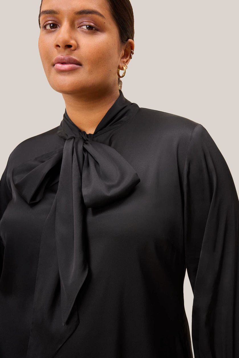 Close-up of bow tie neckline and keyhole on black satin blouse