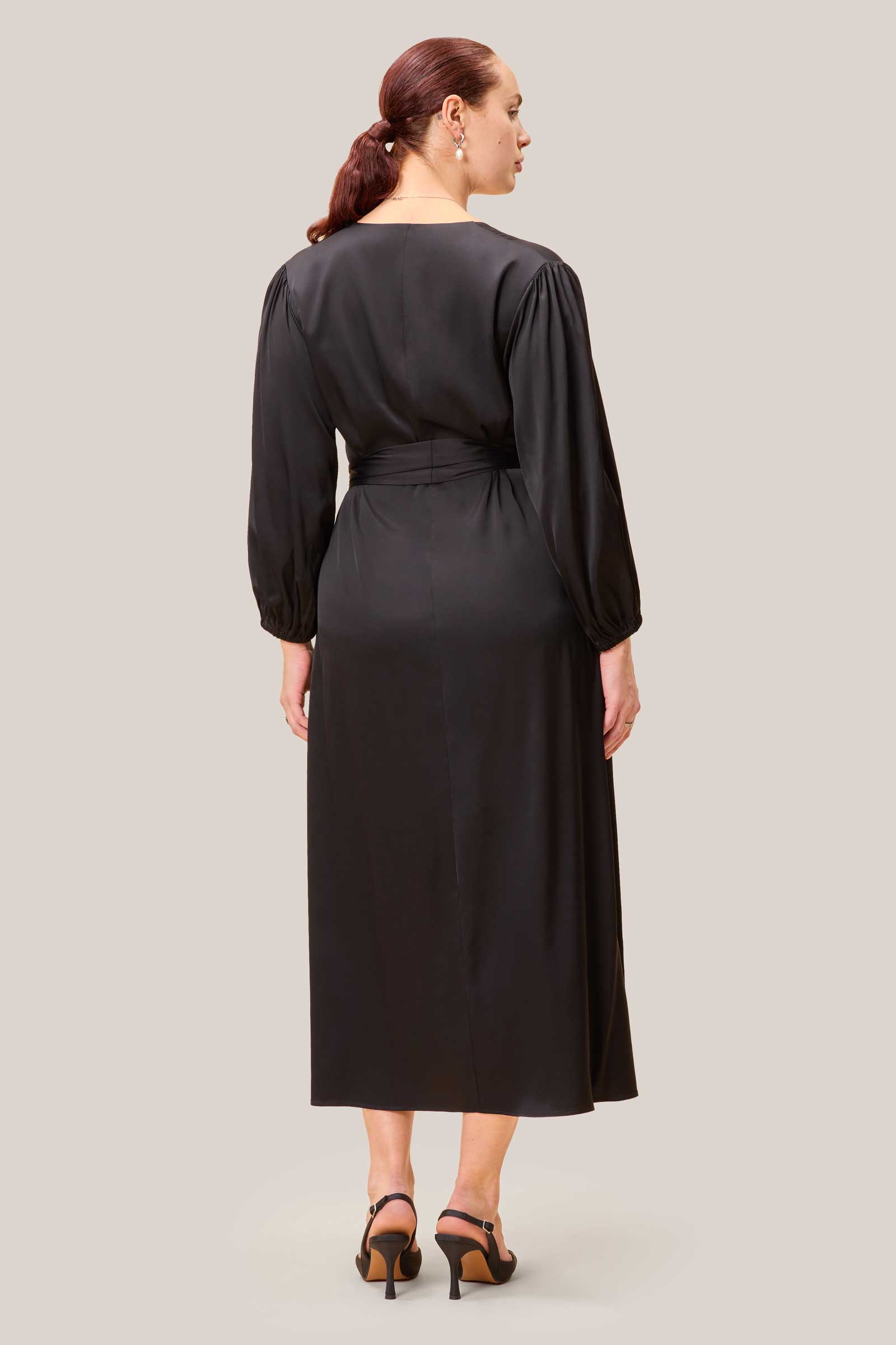 Back of black A-line midi dress with removable belt and fluid movement.