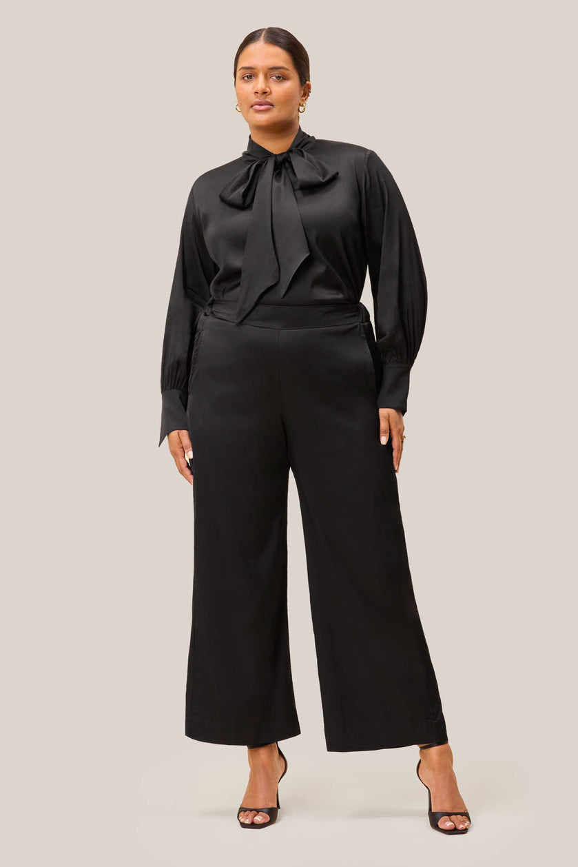 Full front view of model in black satin plus size palazzo trousers. THE HOUR