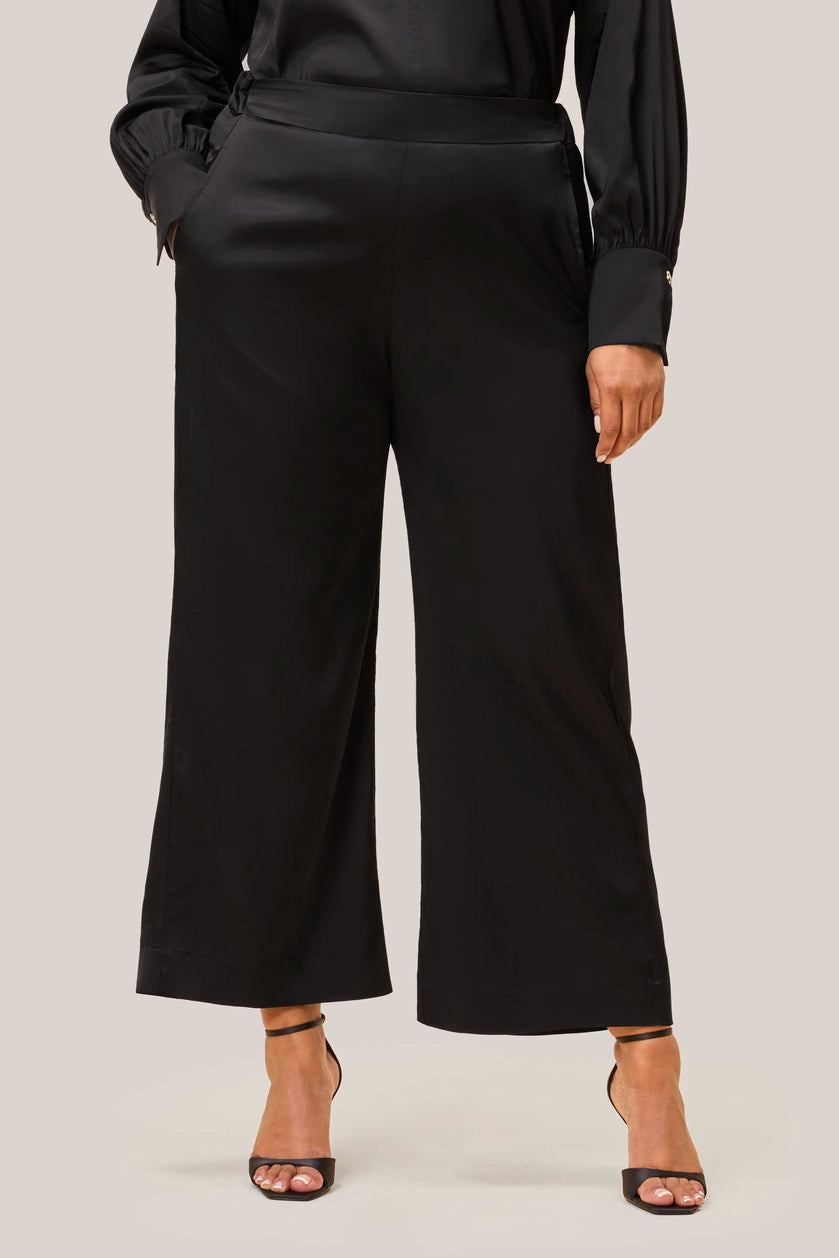 Front view of model in black satin palazzo trousers