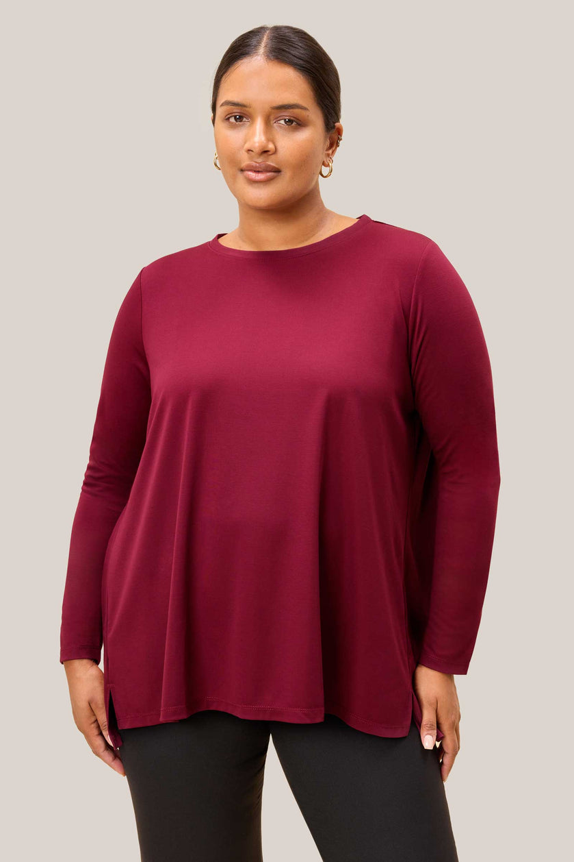 Close-up of burgundy jersey fabric and side slit detail on plus size top. THE HOUR
