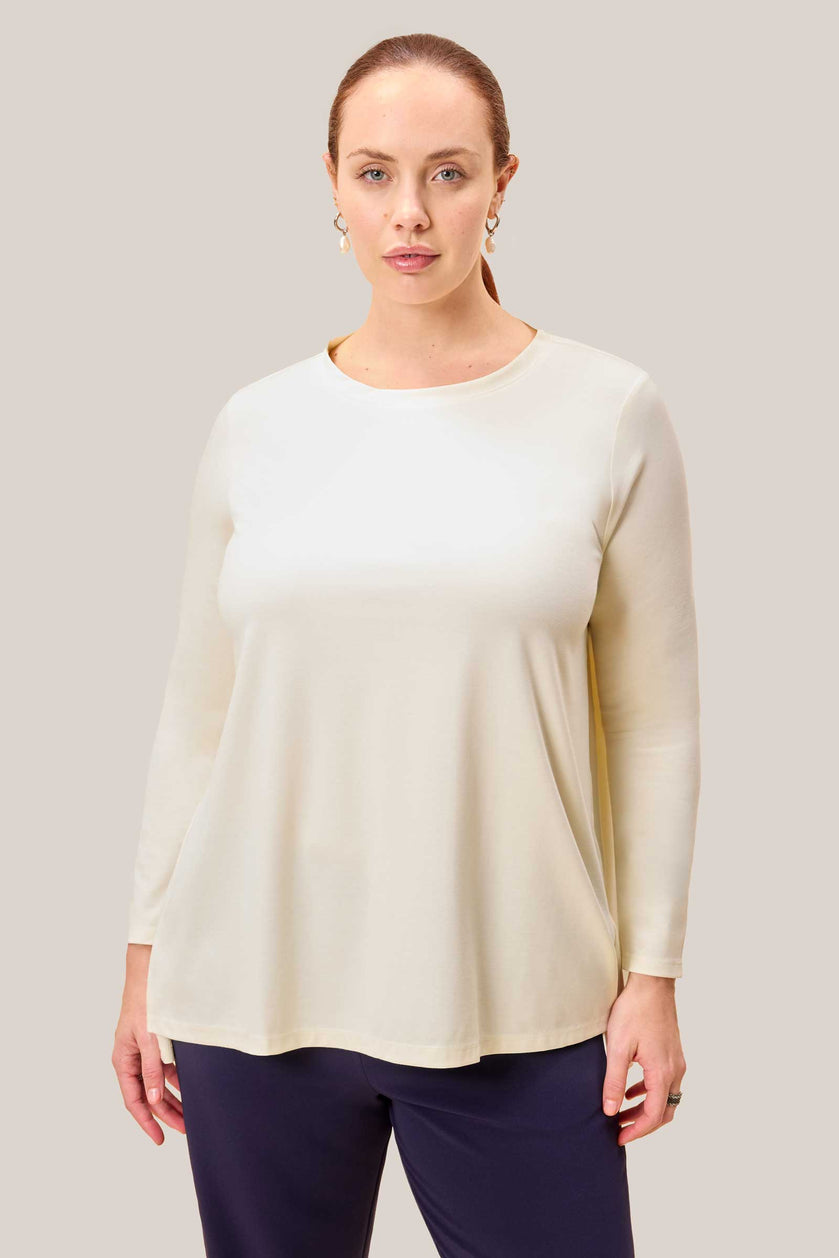 Front close-up of model wearing plussize cream jersey top with round neckline. THE HOUR