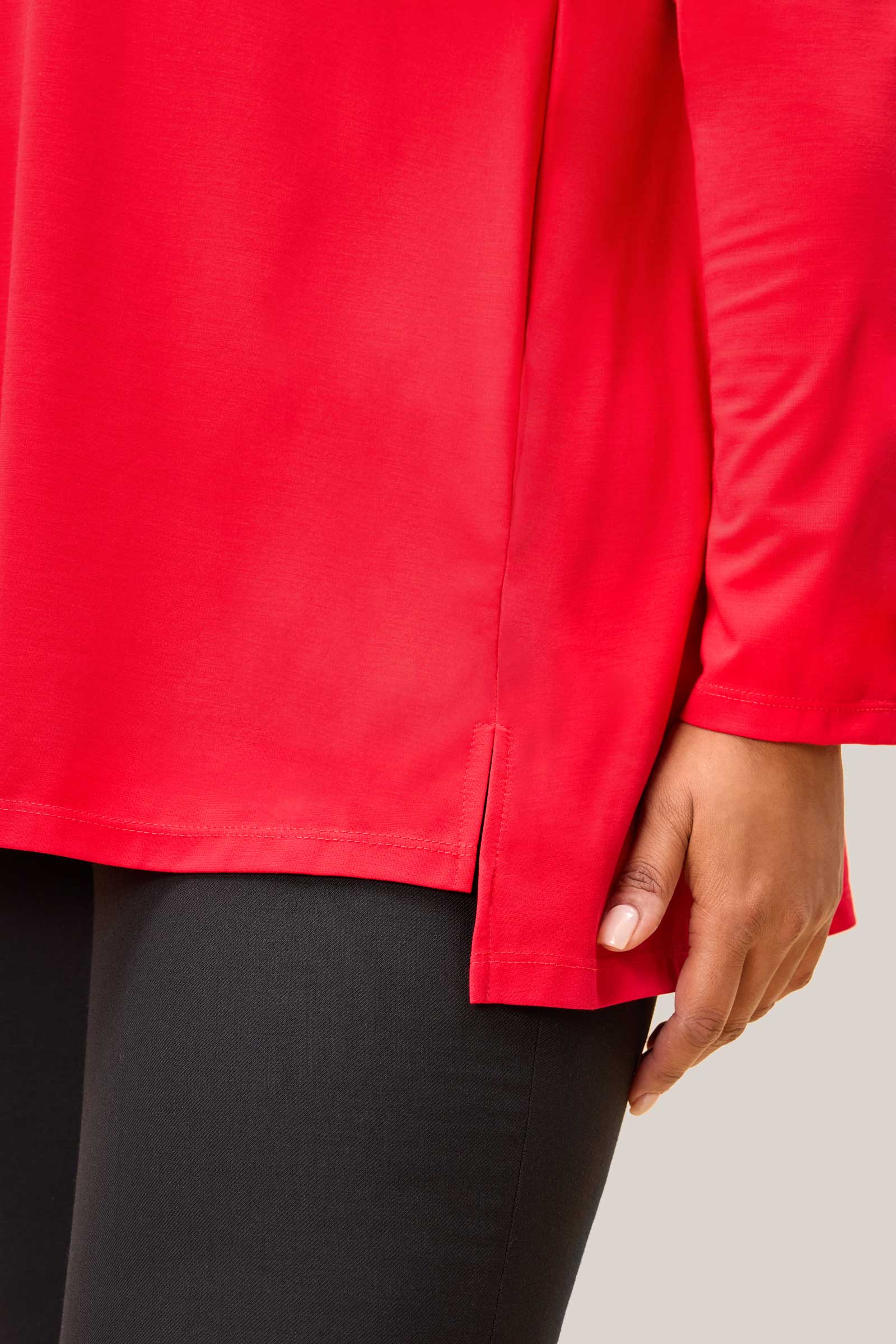 Close-up of red jersey fabric and side slit detail on plus size top. THE HOUR