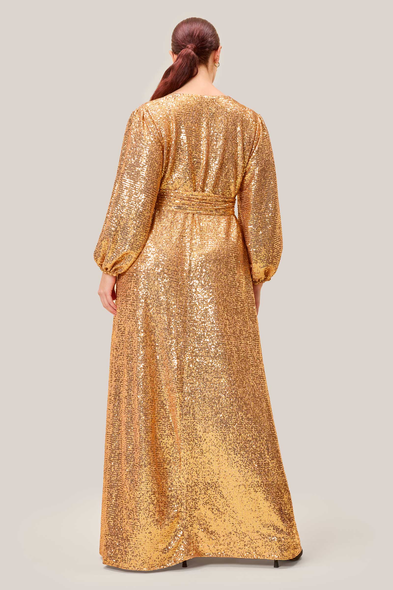 Back view of a plus-size gold sequin gown by The Hour London, showcasing the fluid drape and subtle cinched waist.