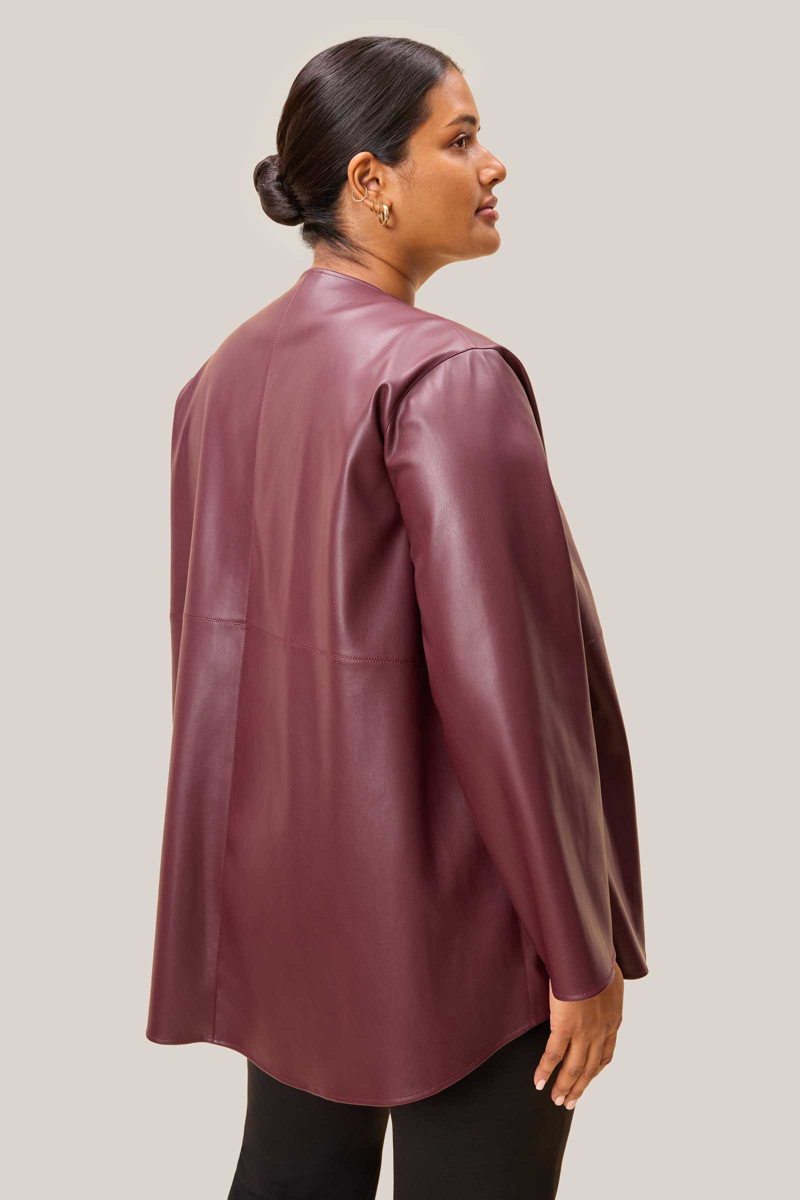 Curvy model wearing a burgundy leather jacket against a plain background