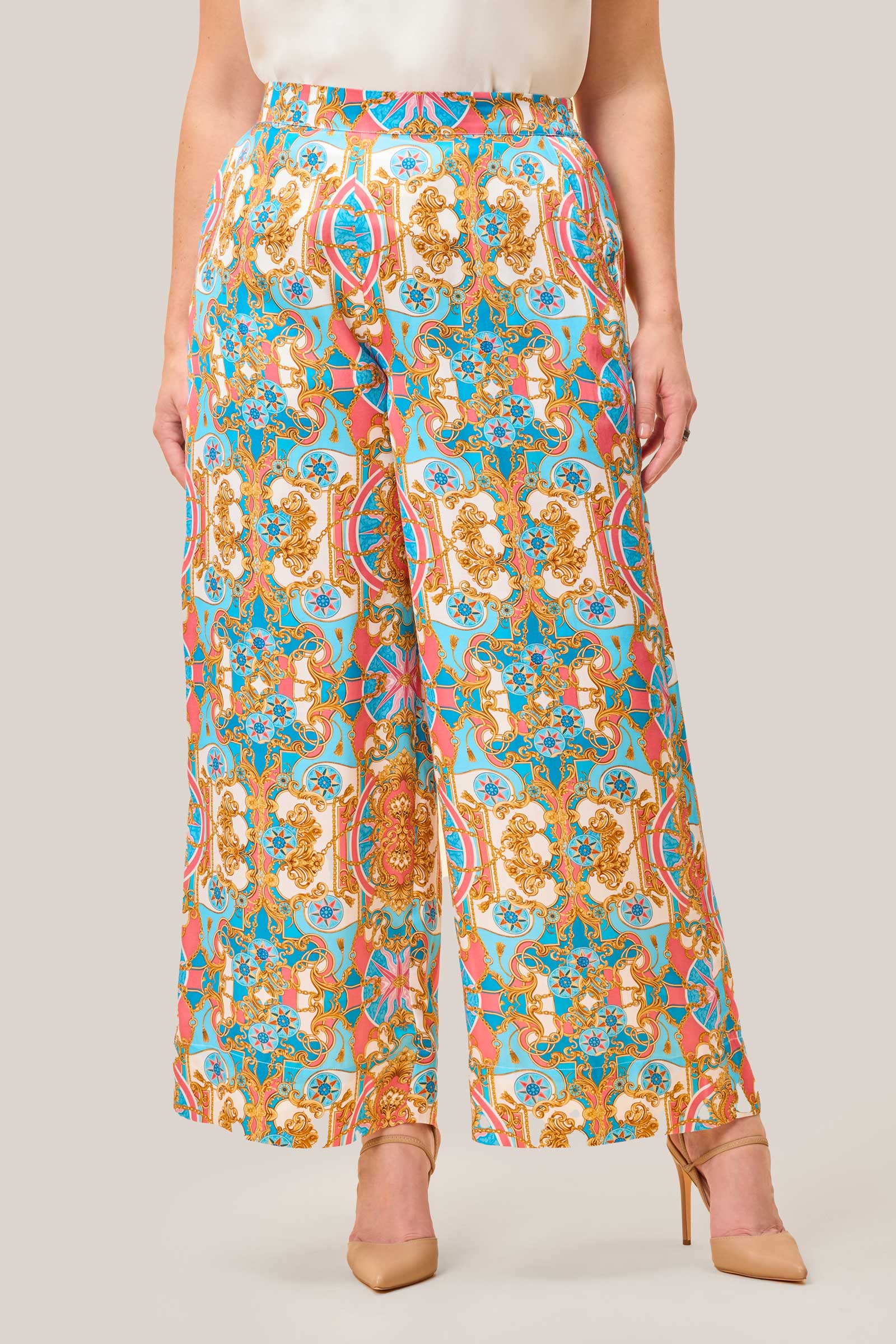 Front view of wide leg satin palazzo trousers with elasticated waistband, baroque-inspired multi-colour print in coral pink, gold, and aqua blue.