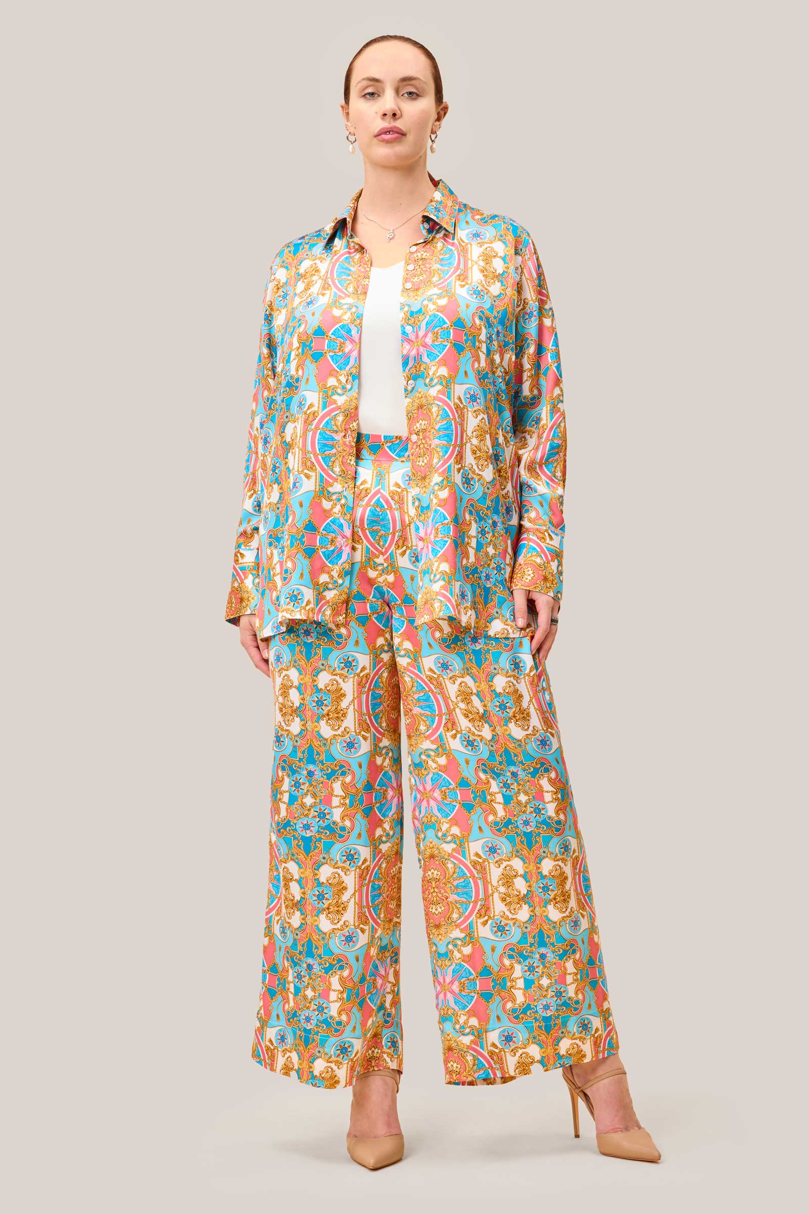 Plus size model wearing matching satin baroque print shirt and wide leg palazzo trousers set, styled with nude heels. THE HOUR