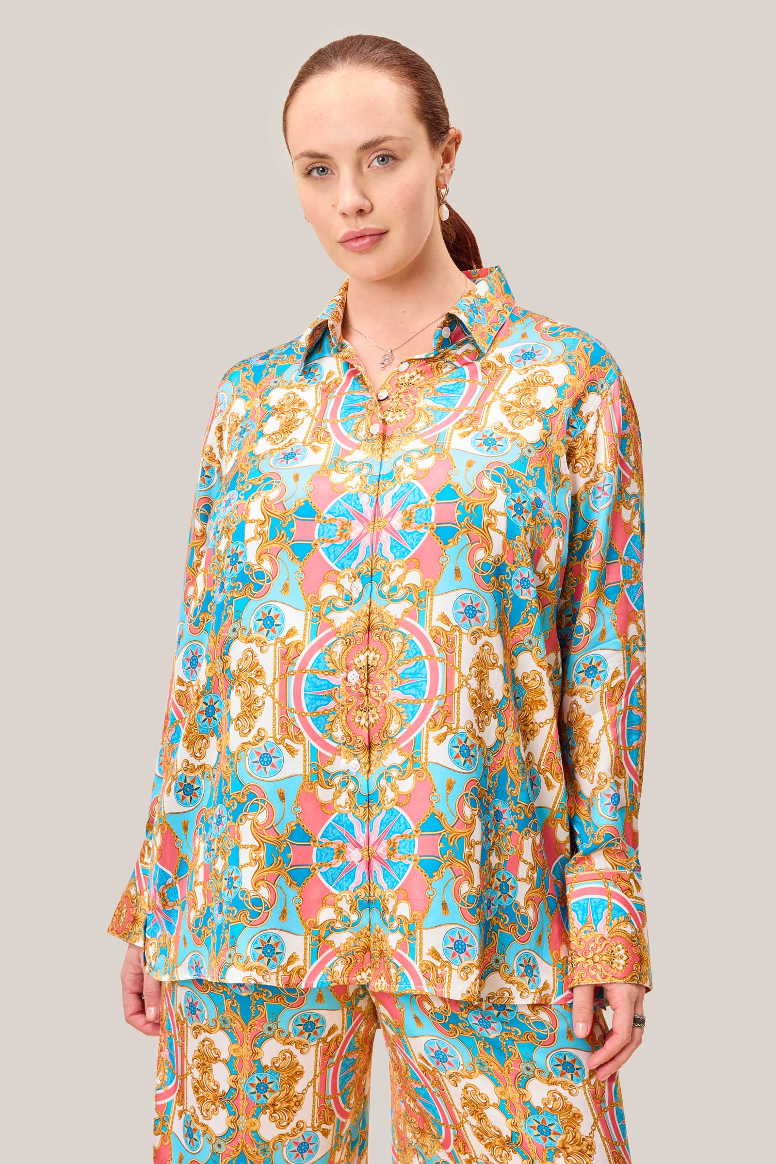 Plus size model wearing baroque print satin viscose shirt in coral pink, aqua blue, and gold with concealed interior button for a no-gape finish.