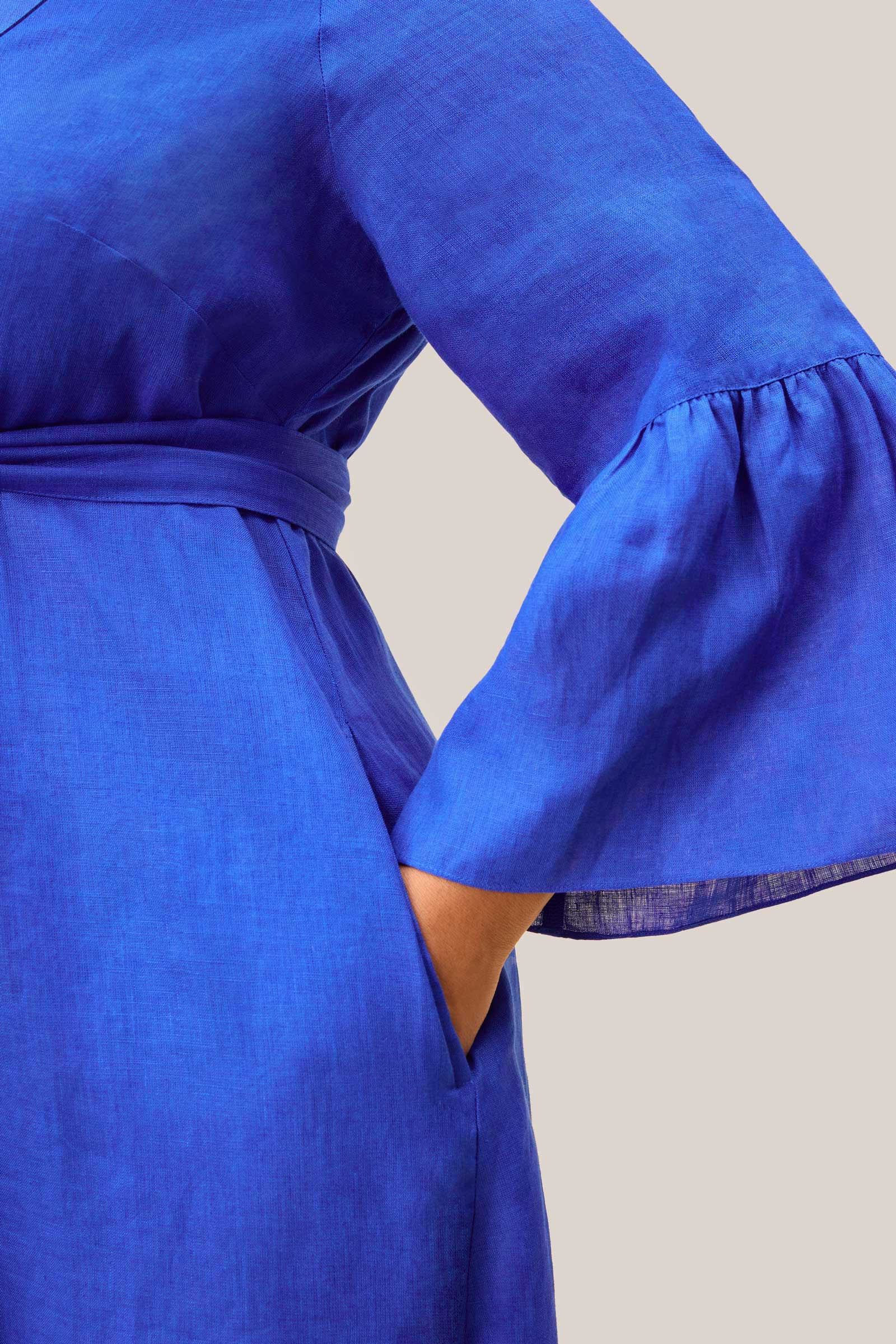 Close-up of bell sleeve and side pocket on royal blue linen midi dress
