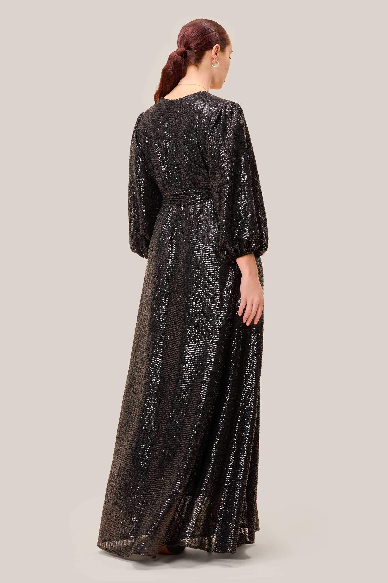 Back view of a black sequin plus-size gown with a soft drape and cinched waist, designed by The Hour