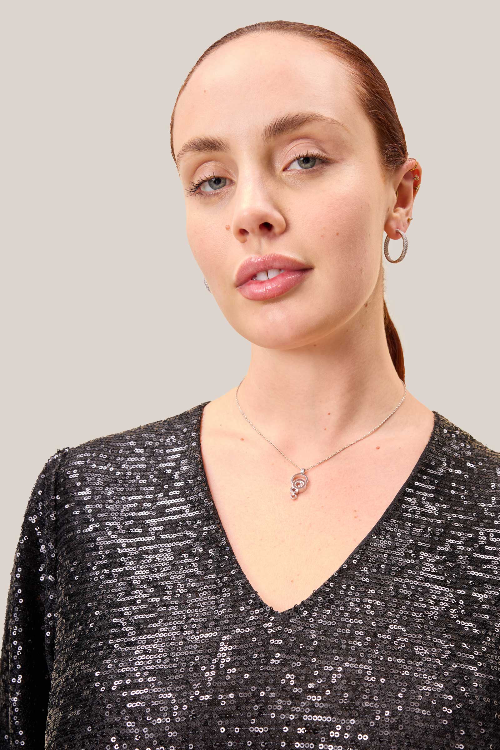 Detail of the V-neckline in shimmering black sequins on a plus-size model.