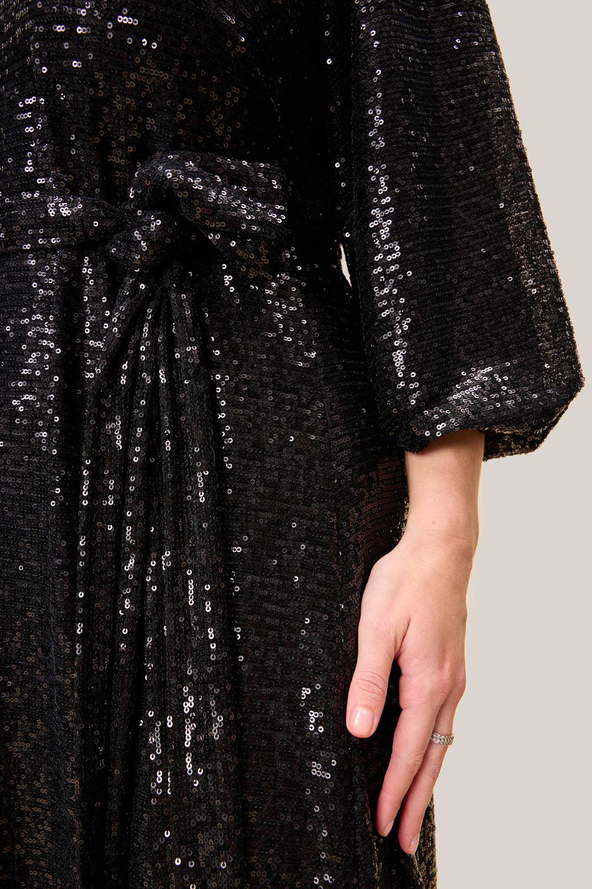 Close-up of a plus-size black sequin gown showing the waist tie and voluminous long sleeves.