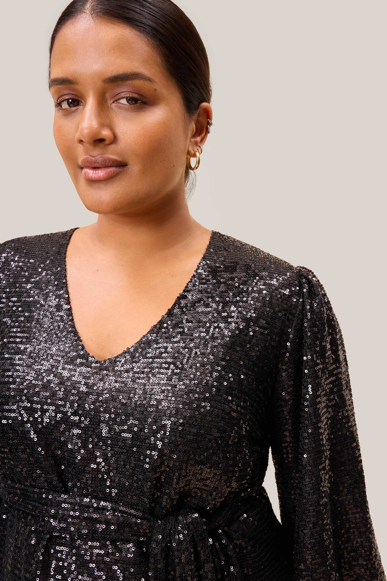 Detail of shimmering black sequins and gathered cuff on a plus-size party blouse by The Hour.