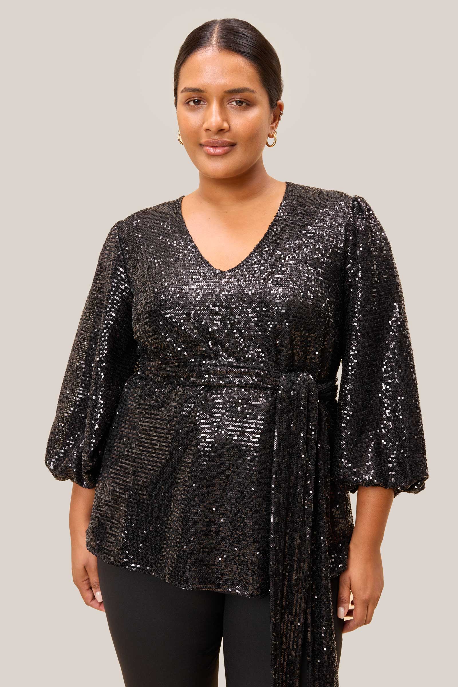 Close-up of a plus-size model in a black sequin blouse with round neckline, from The Hour.