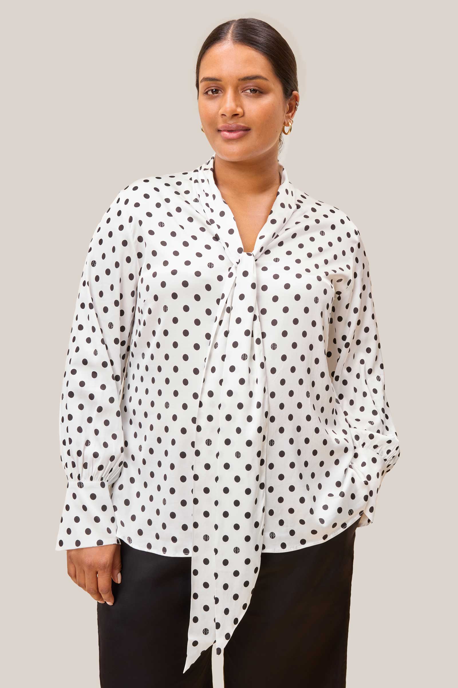 Front view of plus size model in bow tie polka dot blouse