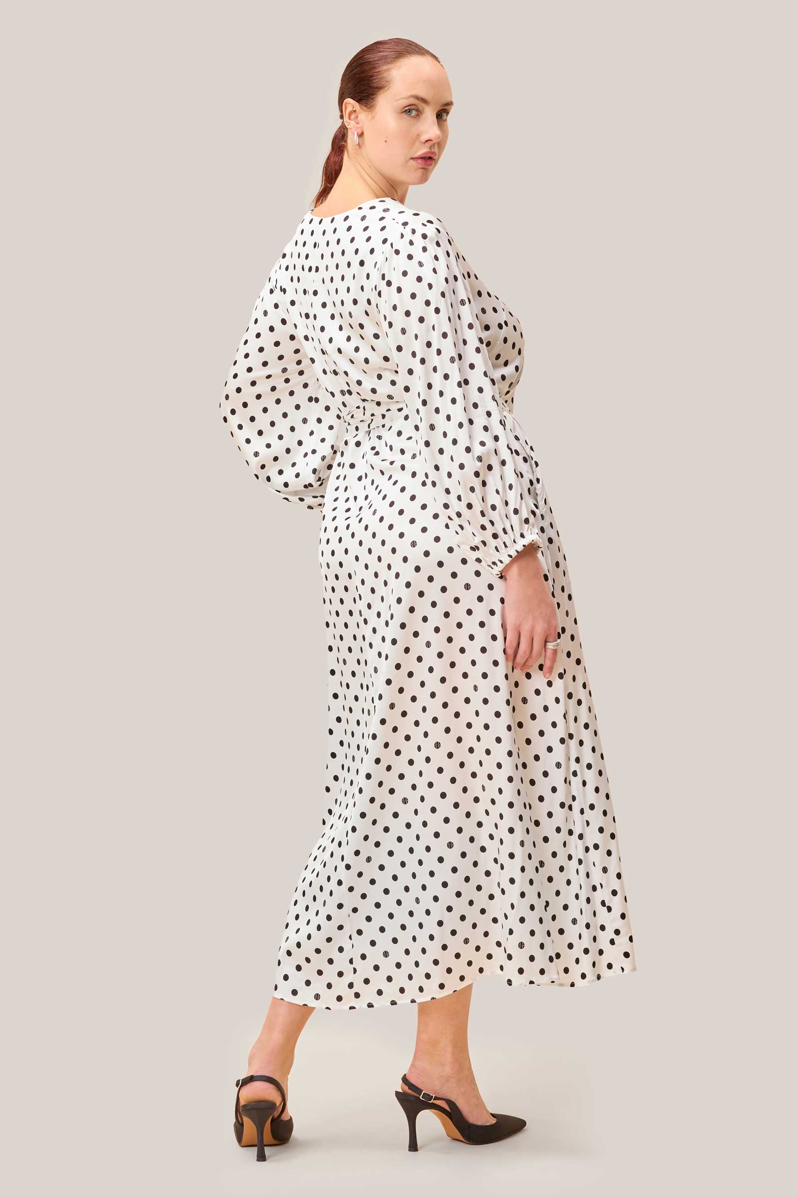 Back view of white midi dress with black polka dots, removable belt and flared hem.