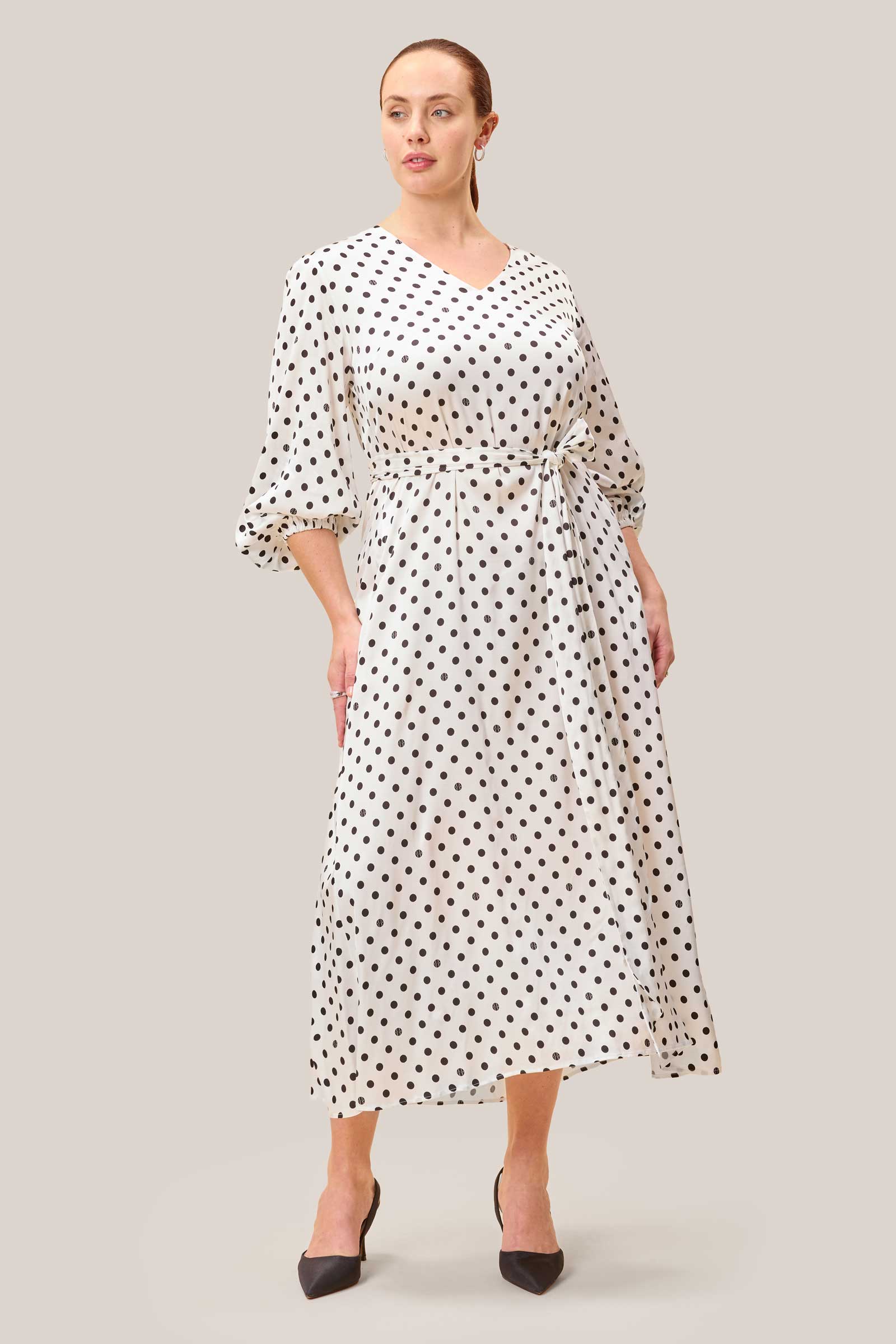 Side view of white satin midi dress with black polka dots and softly gathered sleeves.