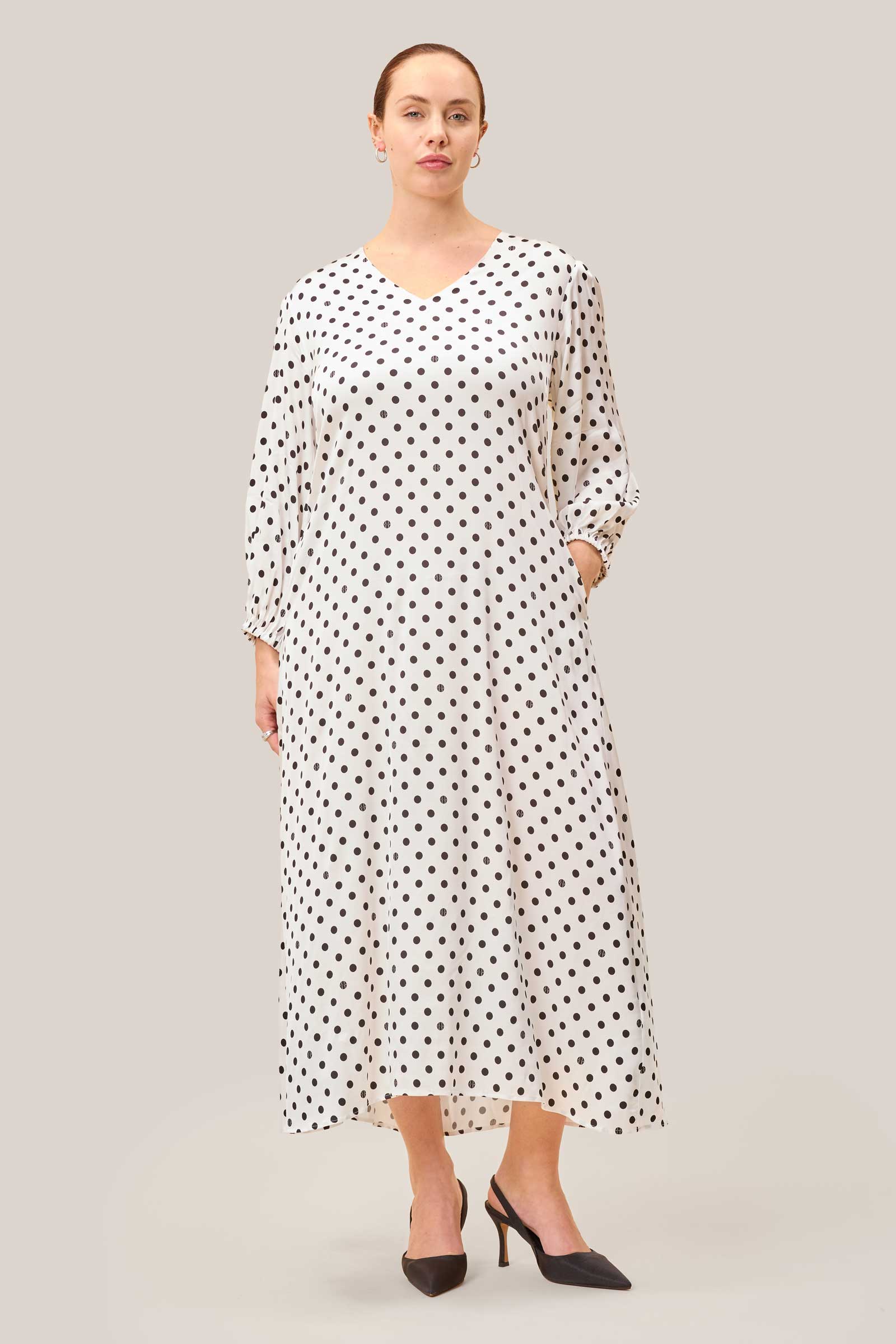Discreet side pocket detail on white satin midi dress with polka dot print.