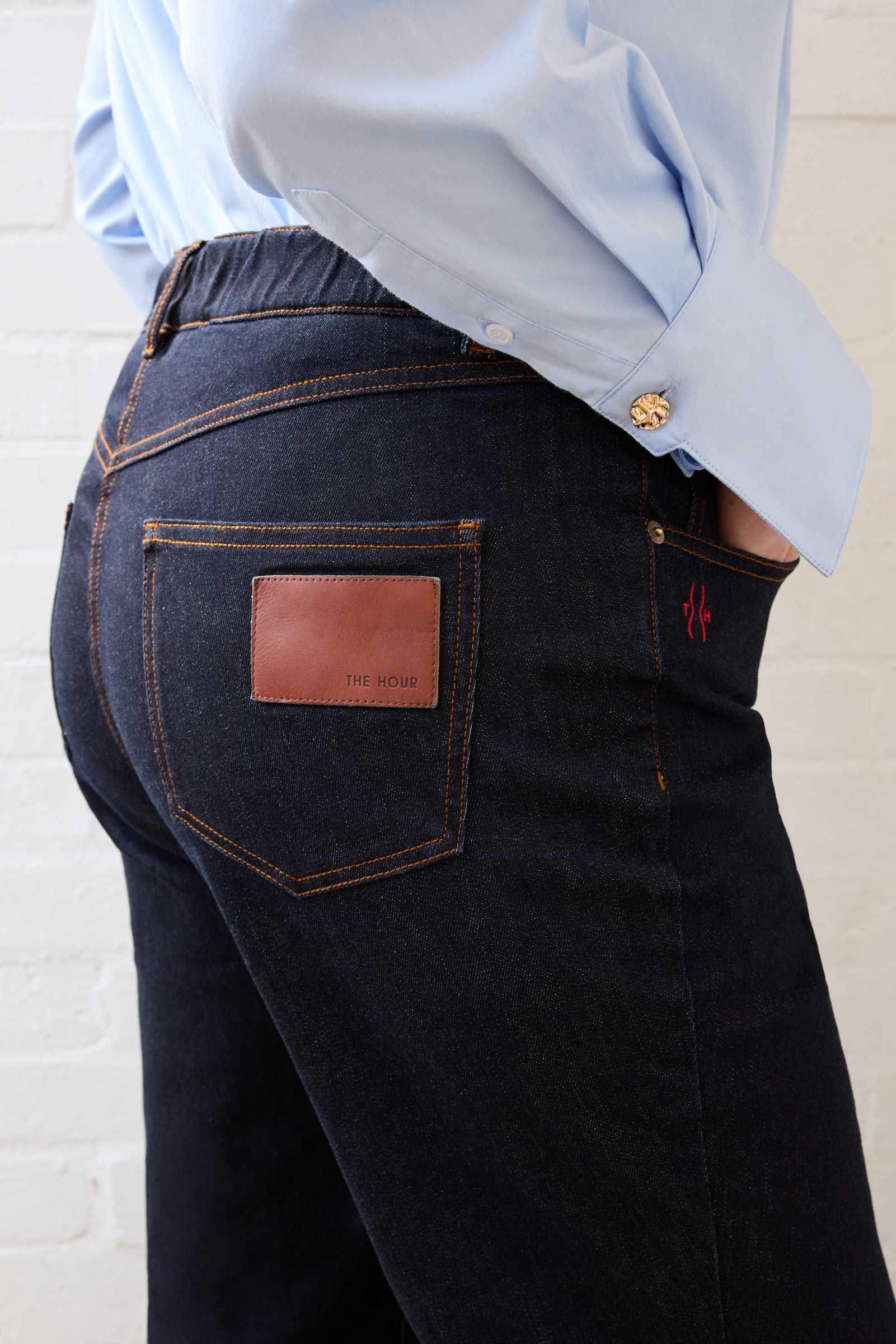 Close-up of logo patch and waistband detail on The Hour’s dark indigo jeans