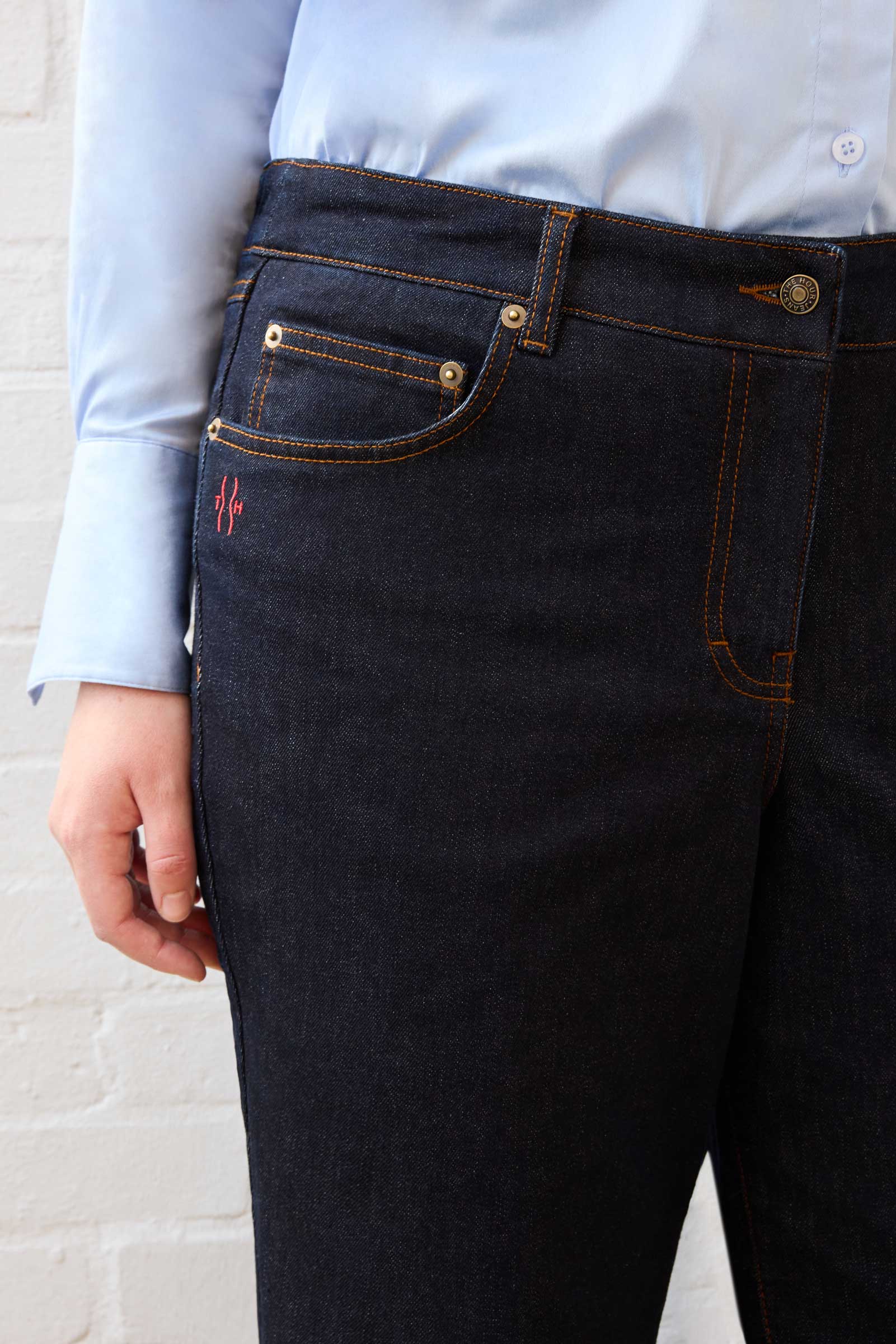 Close-up of logo patch and waistband detail on The Hour’s dark indigo jeans