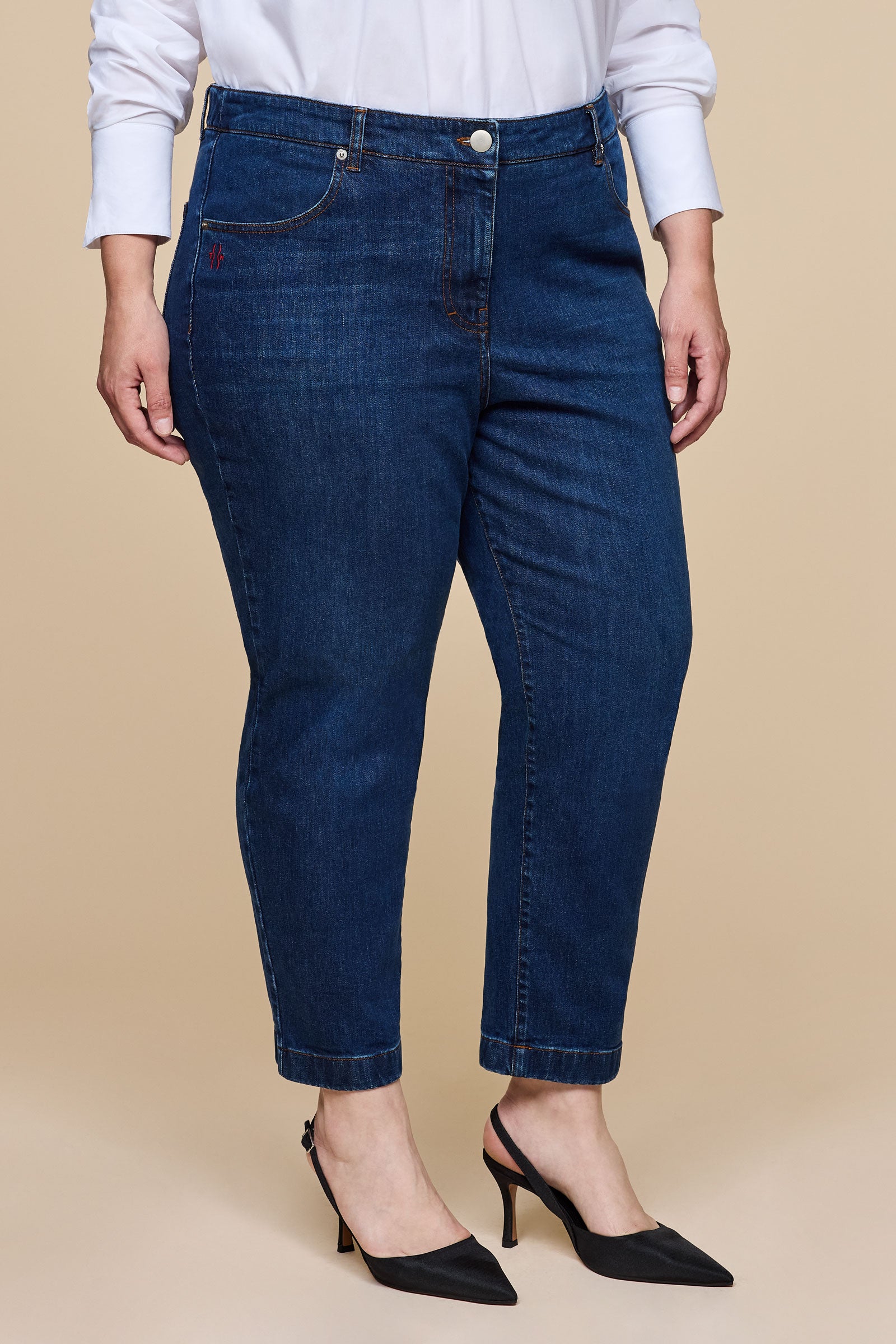 Front view of plus size tapered leg jeans in mid-blue denim, styled with black heels