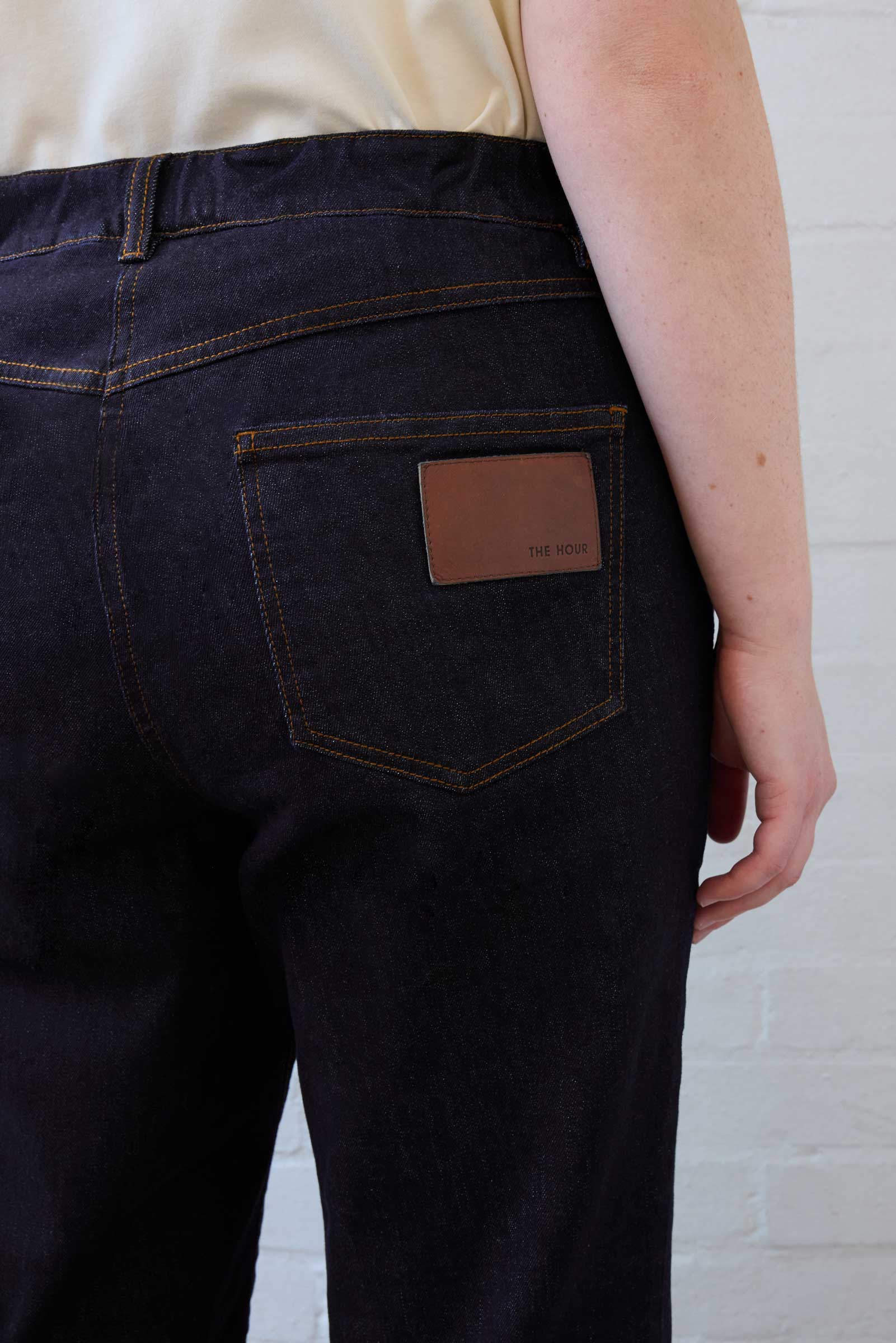 Close-up of leather logo patch on back pocket of The Hour plus size dark indigo jeans