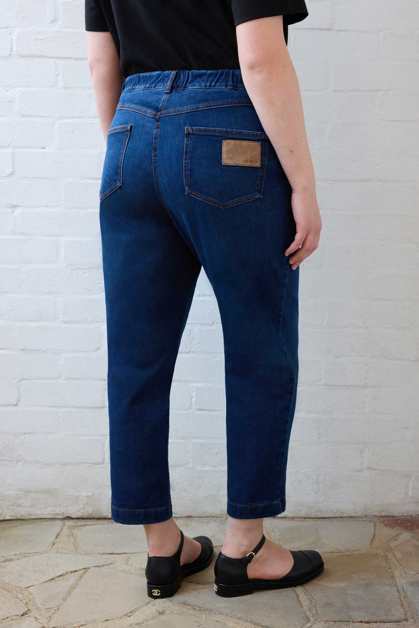 Back view of tapered jeans showing high-rise waist and ankle-length fit