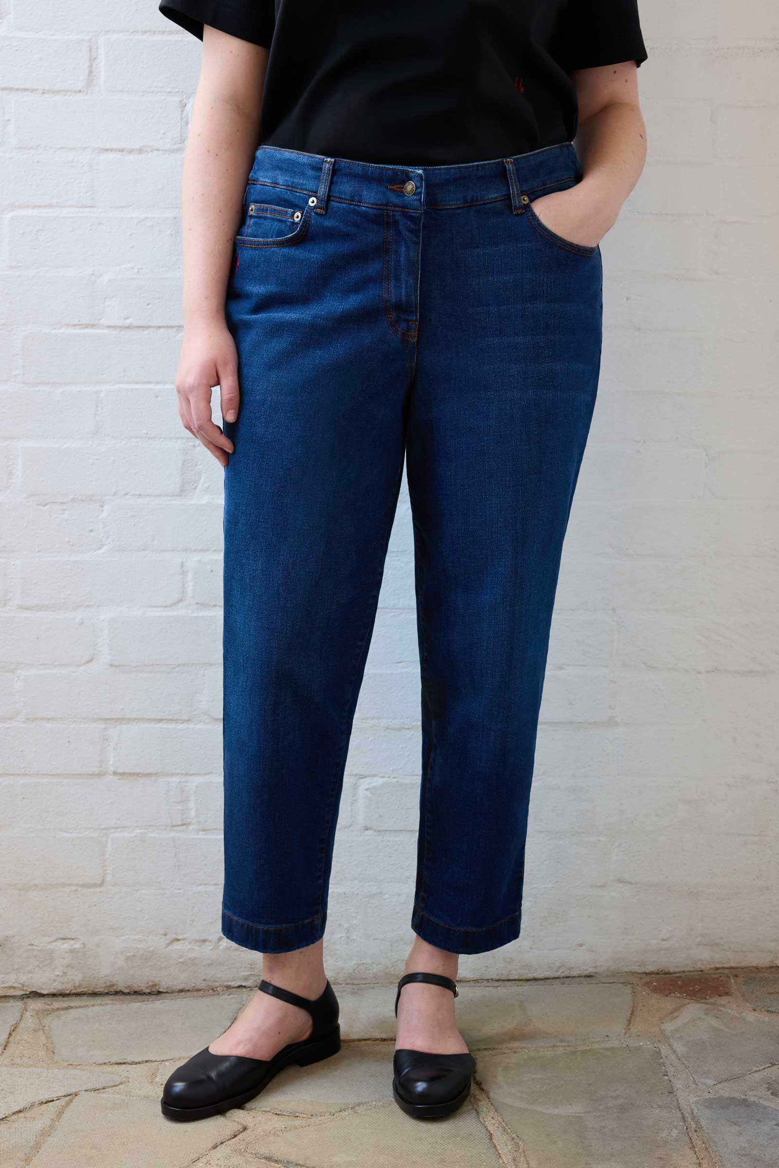 Full front view of plus size tapered jeans styled with black top and flats