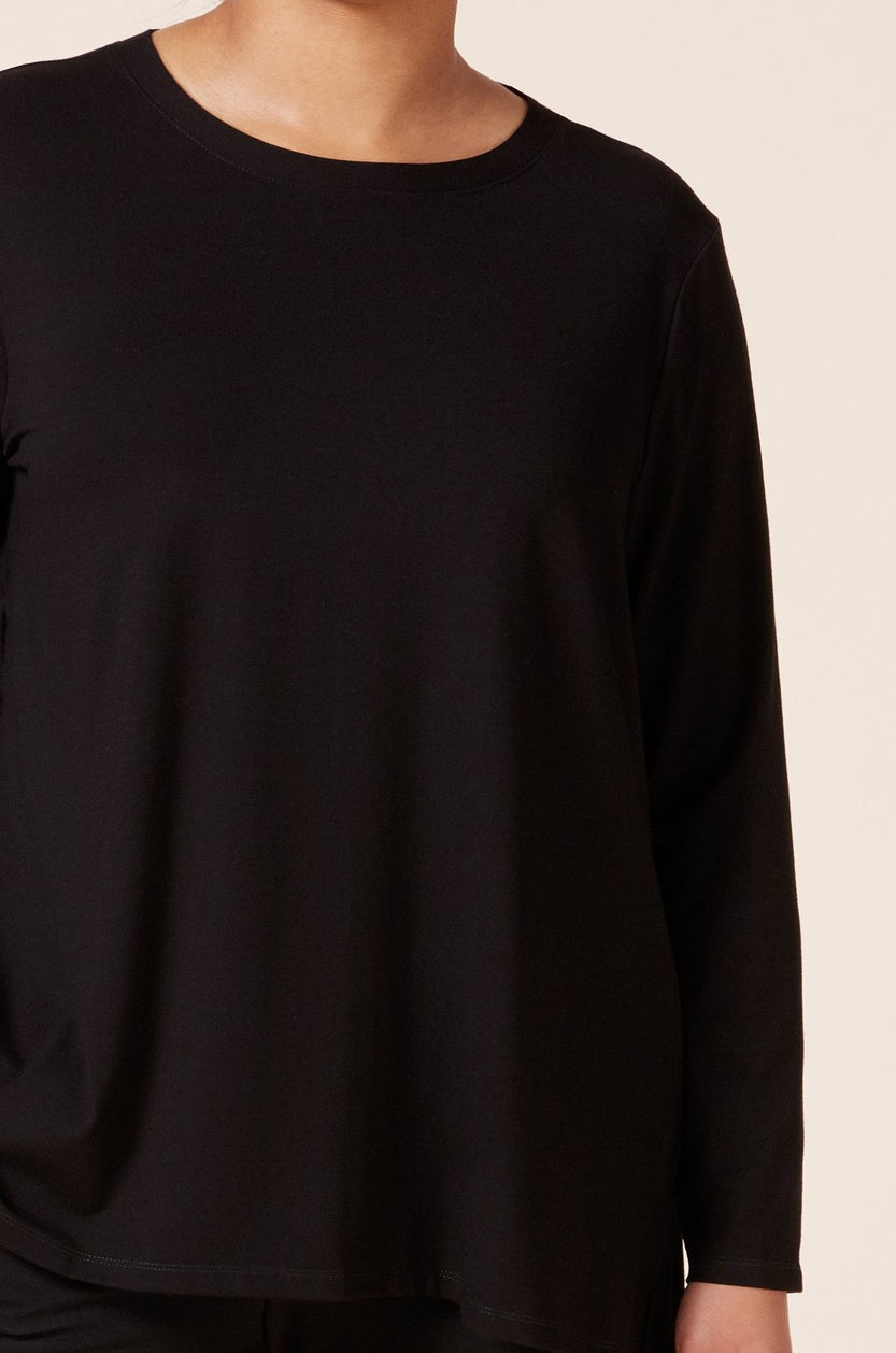 Close-up of black jersey fabric and side slit detail on plus size top. THE HOUR