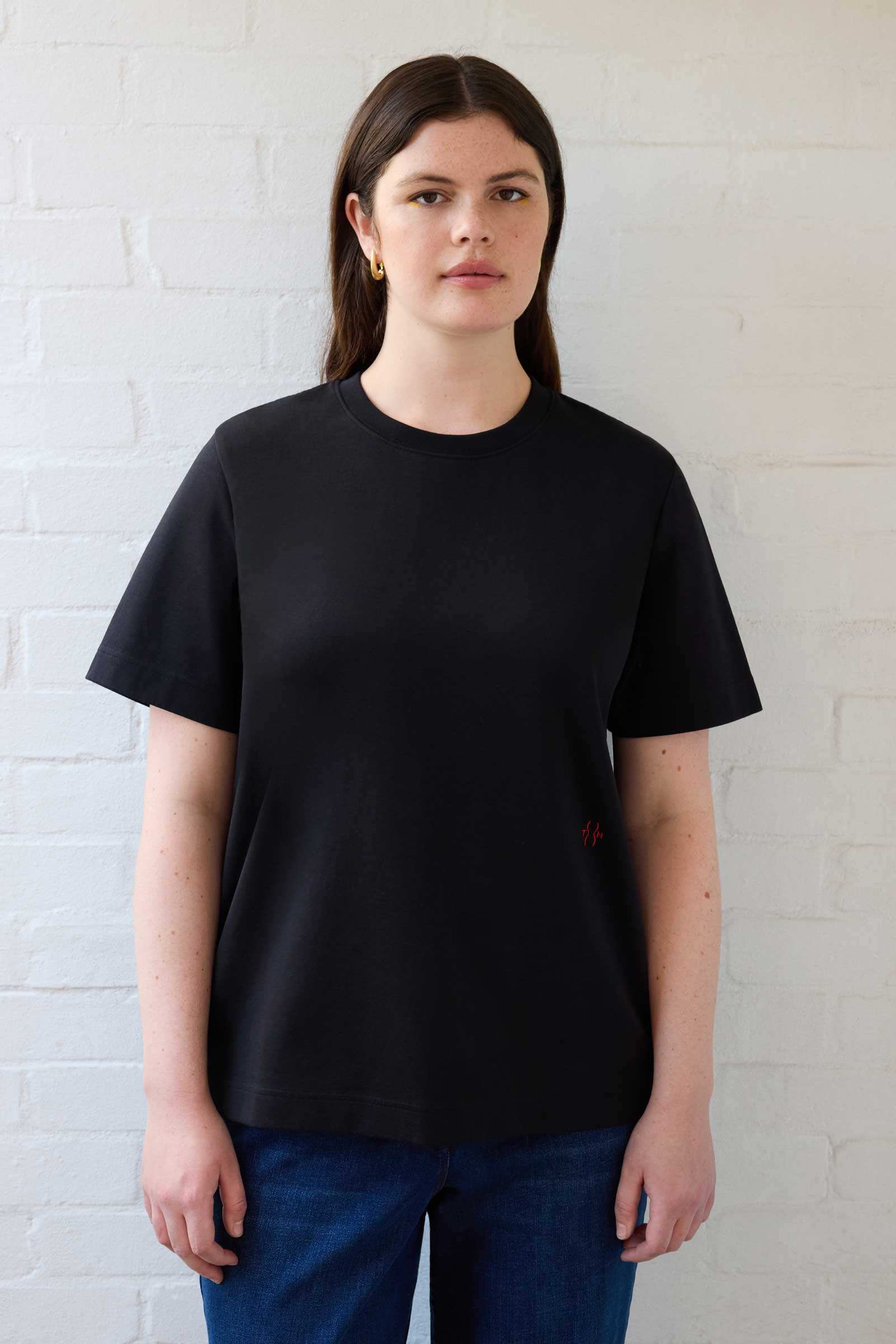 Model wearing black plus size organic cotton T-shirt styled with dark blue denim jeans by The Hour