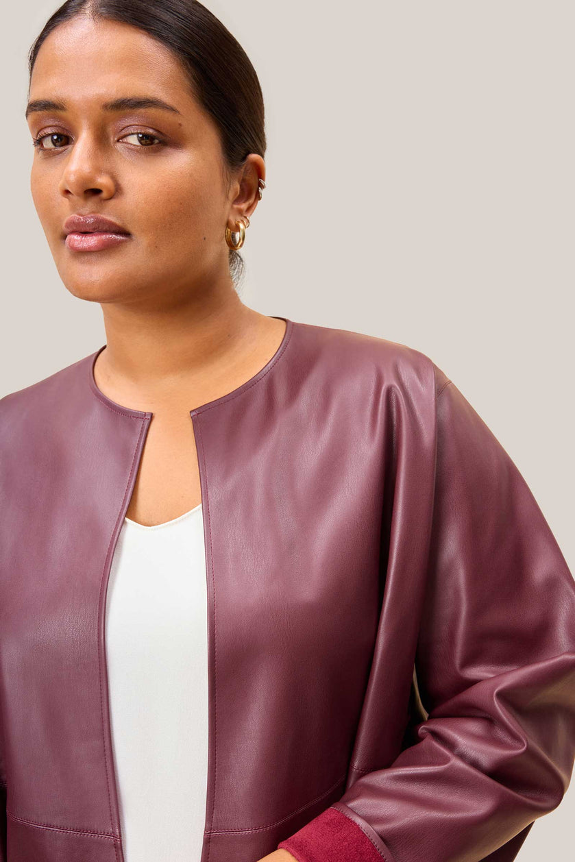 Woman wearing a purple leather jacket against a plain background