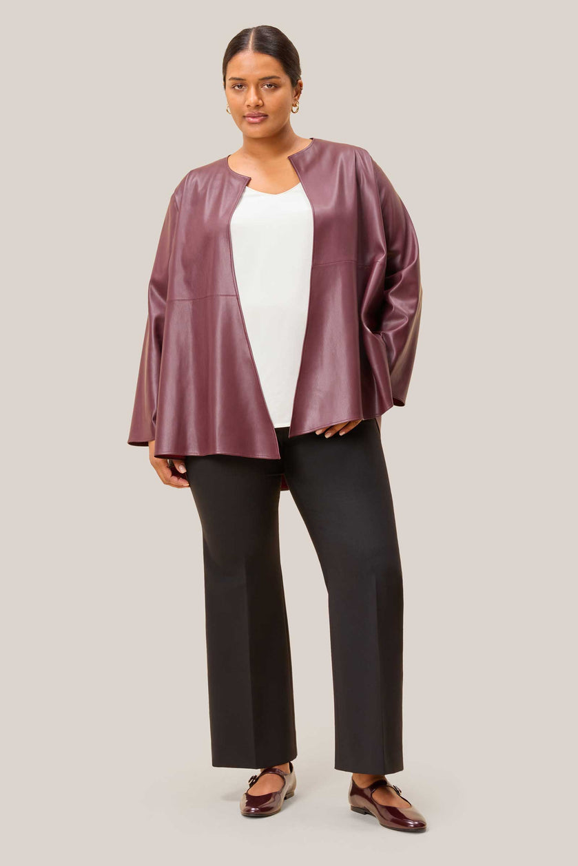 Curvy woman wearing a burgundy leather jacket over a white top and black pants from THE HOUR