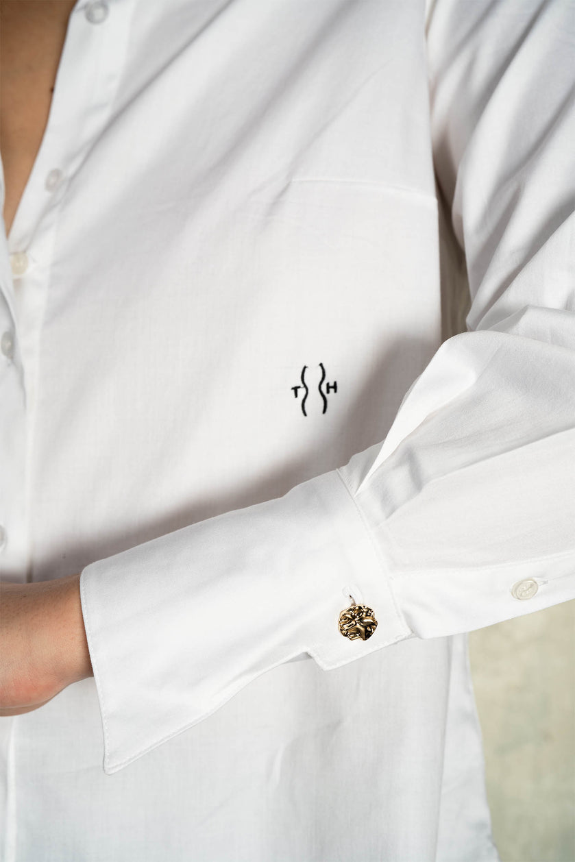 Close-up of gold cuff button on Italian cotton shirt for curvy women – soft sheen fabric texture