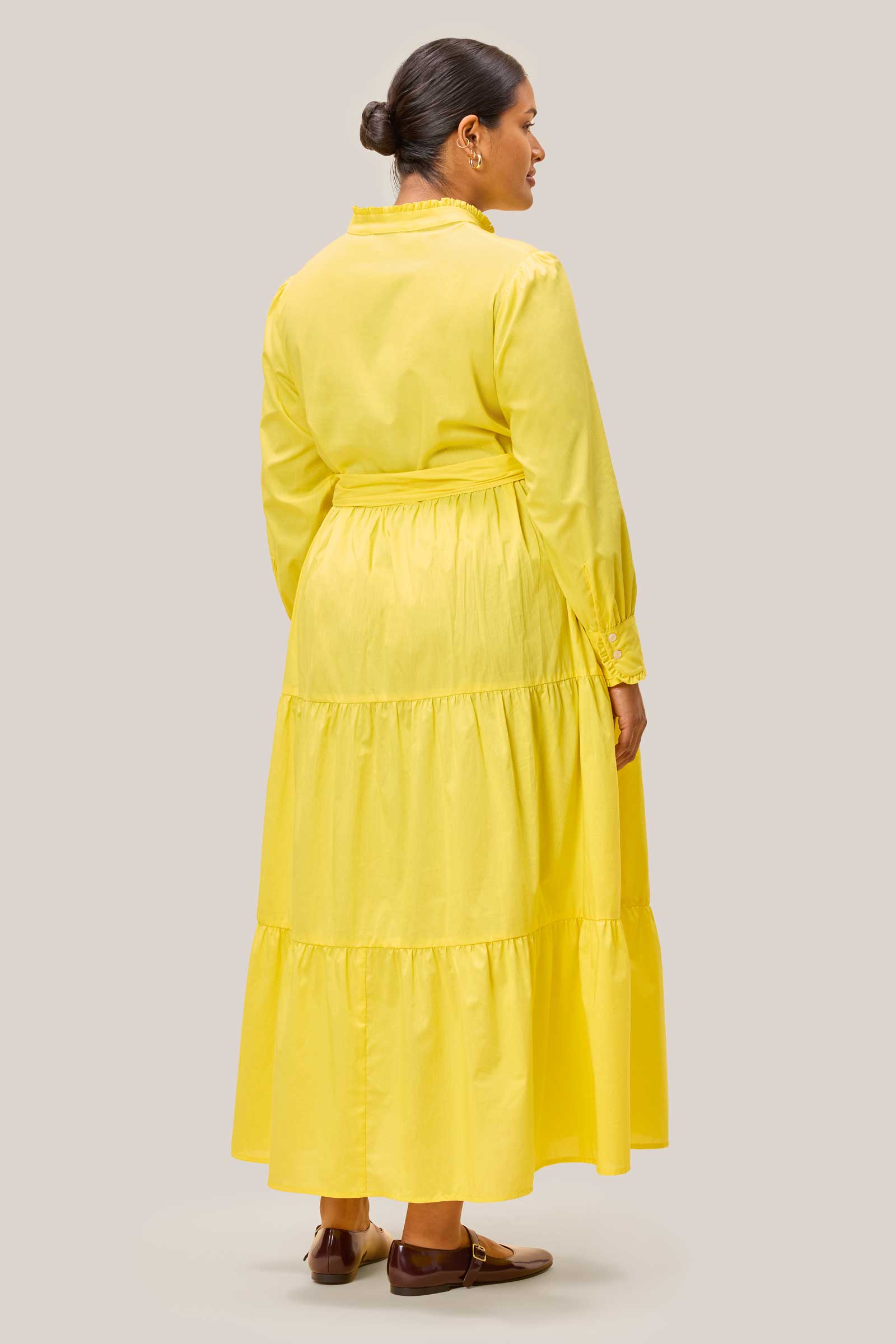 Back view of solid yellow tiered cotton maxi dress on plus size model. THE HOUR